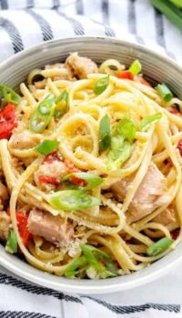 A bowl of pasta with tuna, peppers, and green onions.