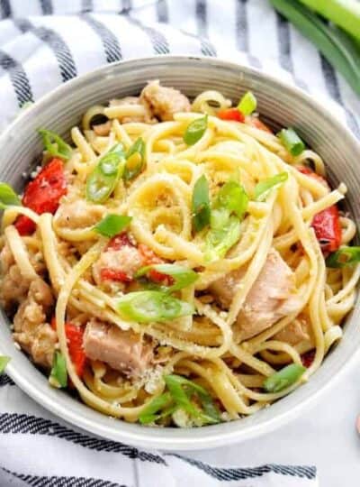 A bowl of pasta with tuna, peppers, and green onions.