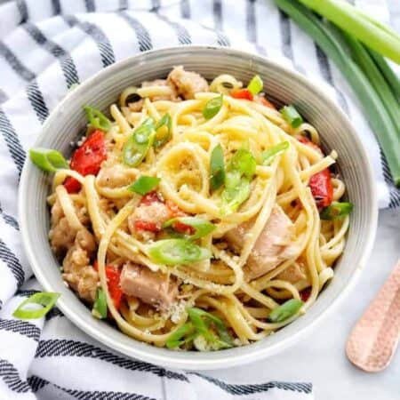 A bowl of pasta with tuna, peppers, and green onions.