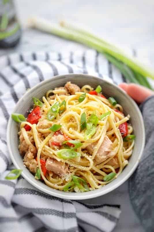 A bowl of pasta with tuna and veggies in a white bowl.