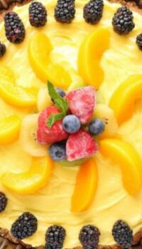 A fruit tart show with blackberries, peaches, and frozen strawberries.