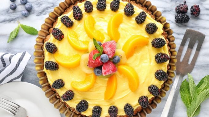 A fruit tart show with blackberries, peaches, and frozen strawberries.