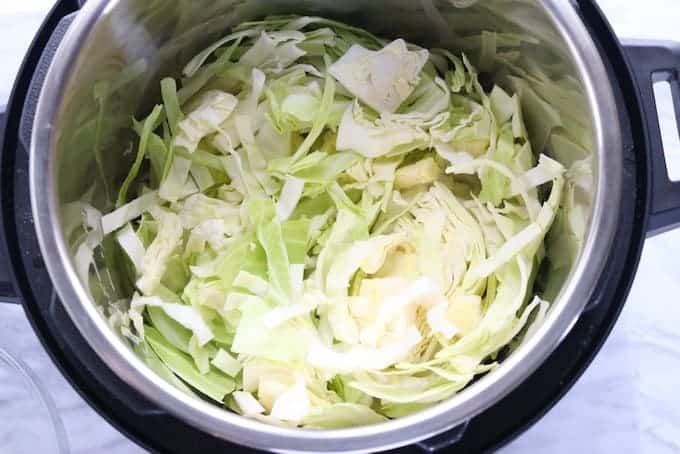 Irish potato and cabbage dish shown being made in an instant pot with cabbage.
