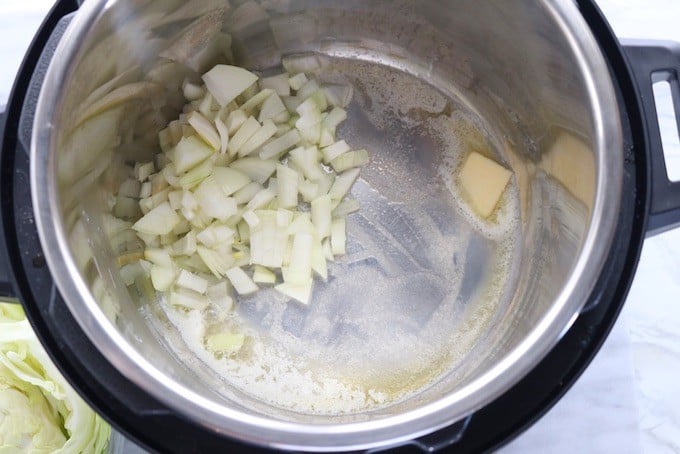 Irish potato and cabbage dish shown being made in an instant pot with melted butter and onions sautéing.
