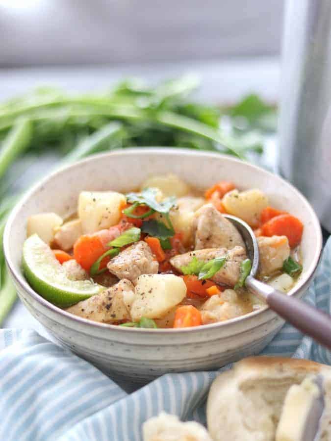 Instant pot chicken stew a pressure cooker soup recipe shown in a white bowl with a spoon topped with green onion and a lime slice. 