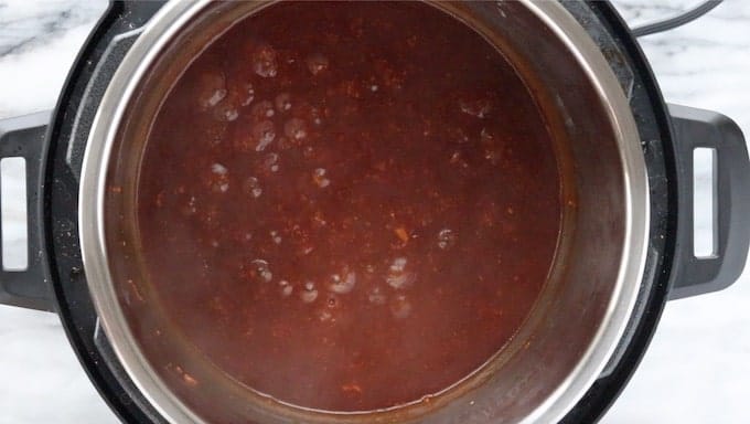 Chinese Honey Chicken sauce shown boiling in the Instant Pot on a white granite surface.