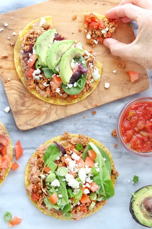 a hand picking up a chicken tostada