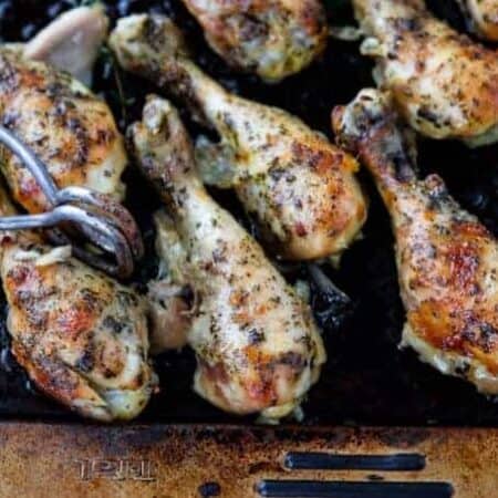 A baking sheet is filled with baked chicken legs.