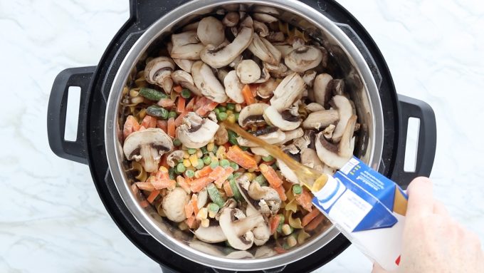 Instant pot beef stroganoff recipe showing mixed veggies and mushrooms added and beef broth being poured into the instant pot. 