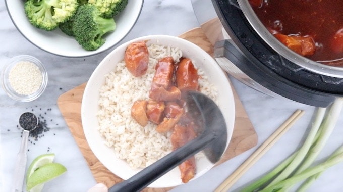 honey chicken being added to a bowl of rice