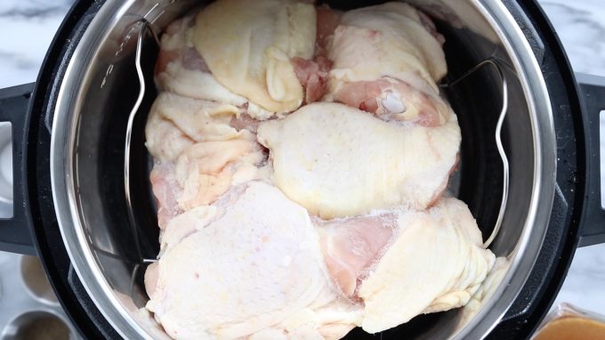 Instant Pot Frozen Chicken Thighs showing frozen, raw chicken thighs in the Instant Pot on top of the Instant Pot rack.