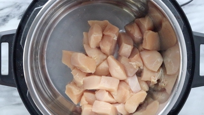 Chinese Honey Chicken showing bite-sized chicken pieces being cooked in the Instant Pot with hot oil.