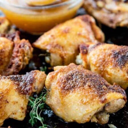 Cooked chicken thighs are shown on a baking sheet after broiling.