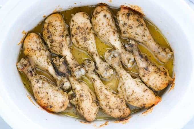 Crockpot Chicken Legs, a flavorful chicken recipe showing cooked chicken legs with spices sprinkled on the top in a white slow cooker.