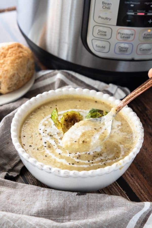 A bowl of food sitting on a table, with Soup and Brussels sprout