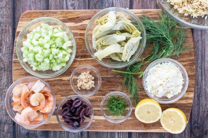 A bunch of food sitting on top of a wooden table, with artichokes and olives