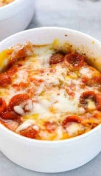 a microwave pizza is shown in a white ramekin with melted cheese and mini pepperonis.