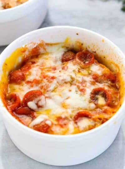 a microwave pizza is shown in a white ramekin with melted cheese and mini pepperonis.