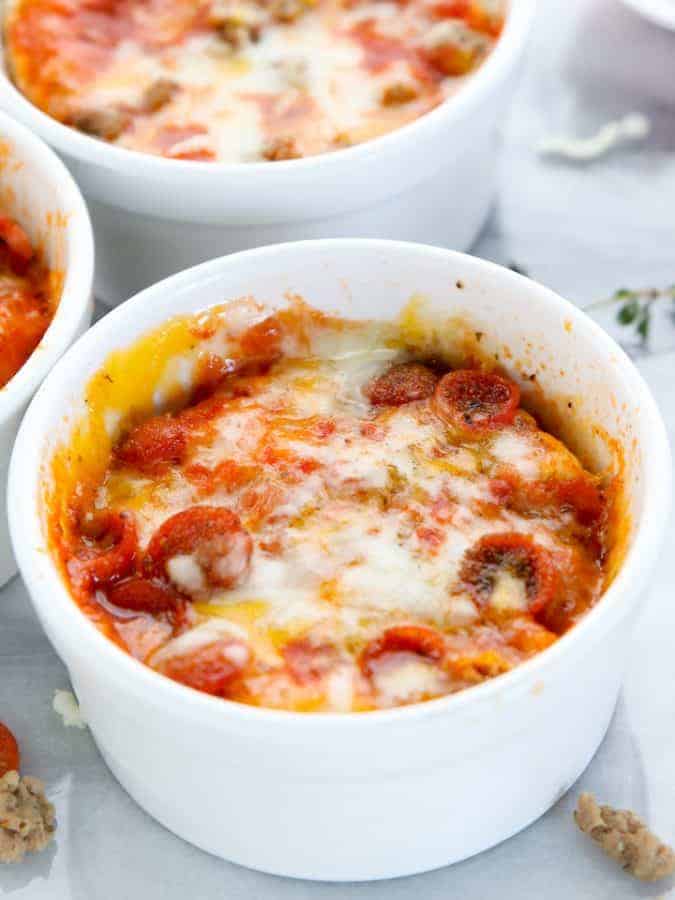 Mug Pizza, a microwave meal being shown in three white ramekins with melted cheese and mini pepperoni all on a white surface.