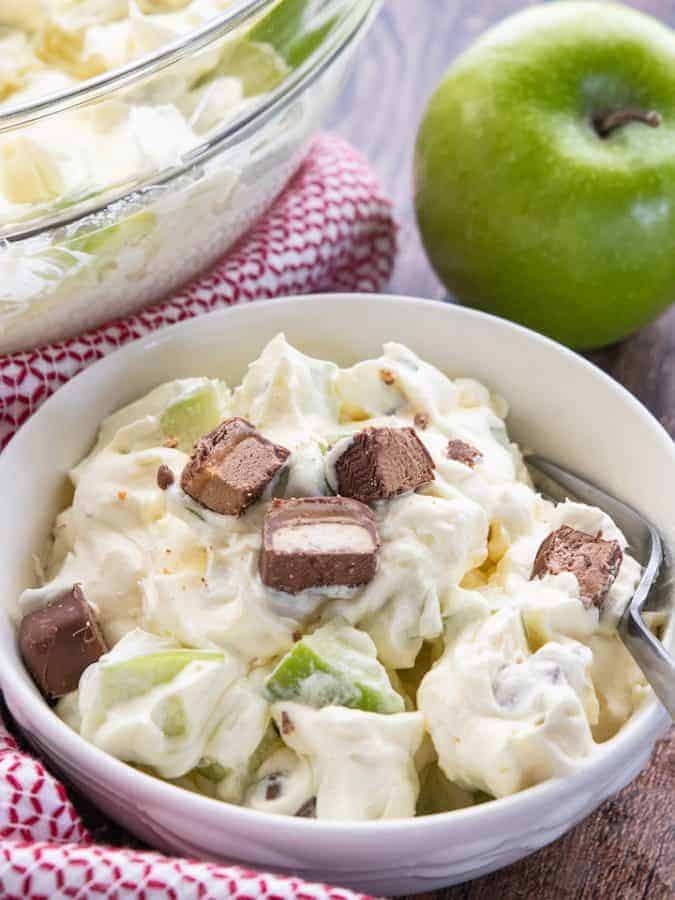 a bowl with apple salad with candy on top