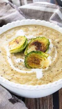Brussels sprout soup shown pureed in a white bowl with roasted Brussels sprouts on top.