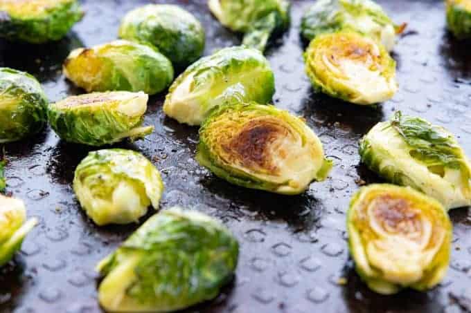 Baked Brussels sprouts, an oven roasted vegetable recipe being shown on a black baking sheet.