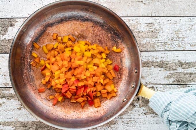 a skillet with diced peppers