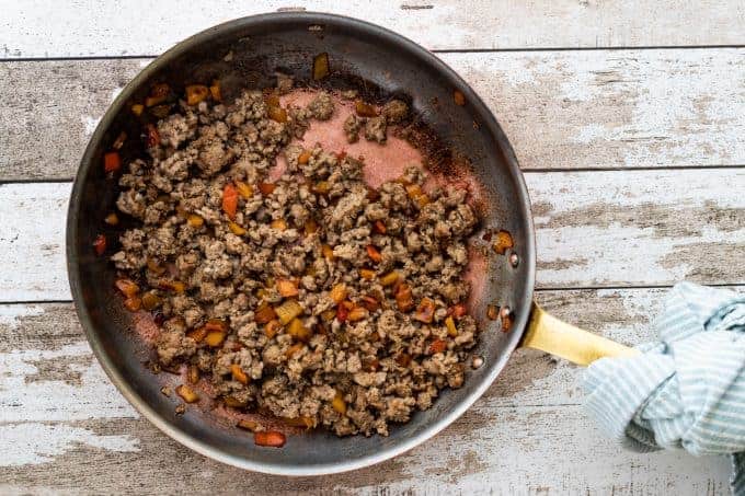 a skillet with ground beef and peppers
