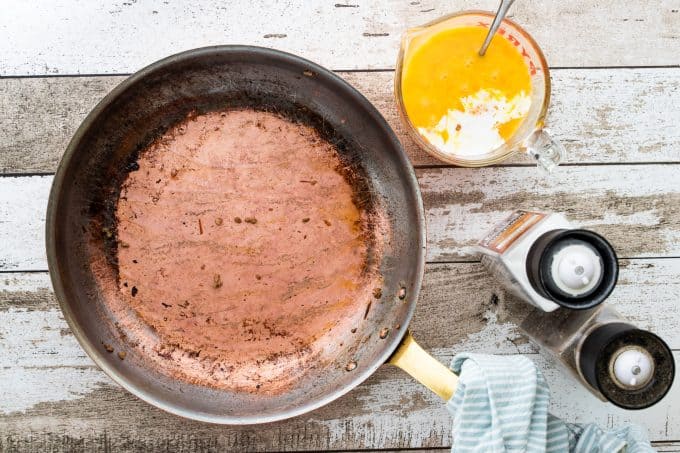 an empty skillet with whisked eggs next to it