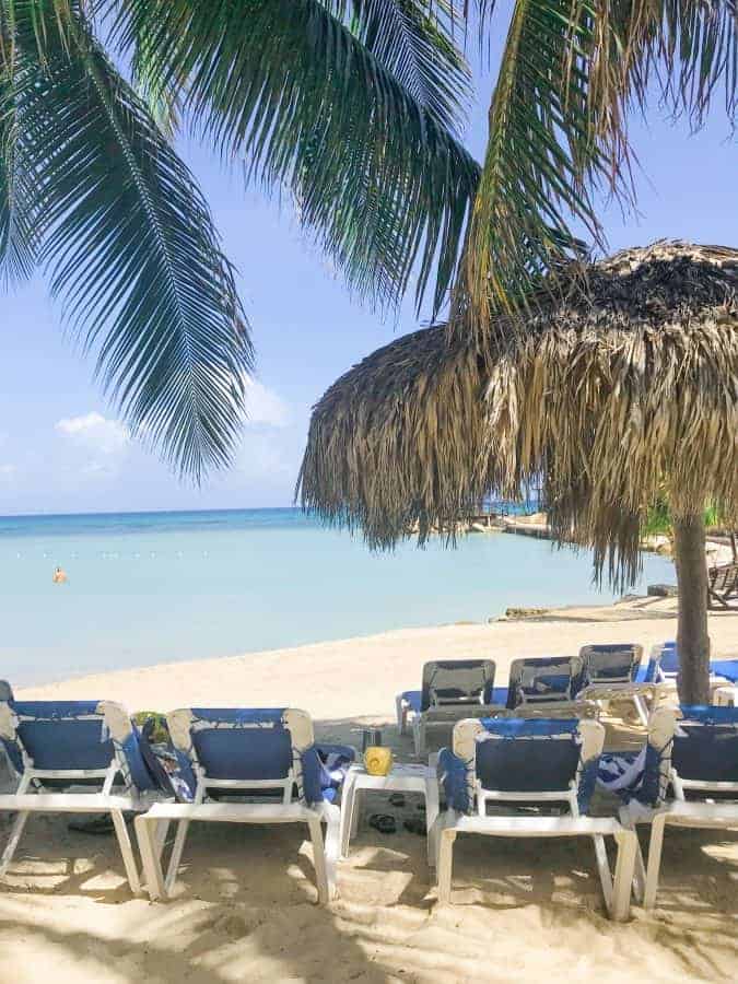 hilton rose hall jamaica beach showing the Caribbean Sea along with sand, beach chairs and a palm tree