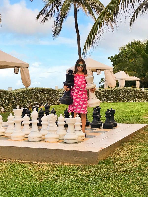 A girl standing on a life-size chess board at the hilton rose hall in jamaica