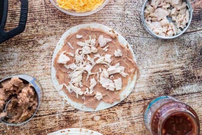 chicken on top of refried beans on a tortilla