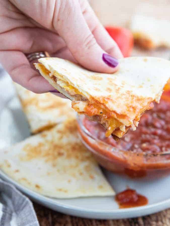 a slice of quesadilla dipped in salsa