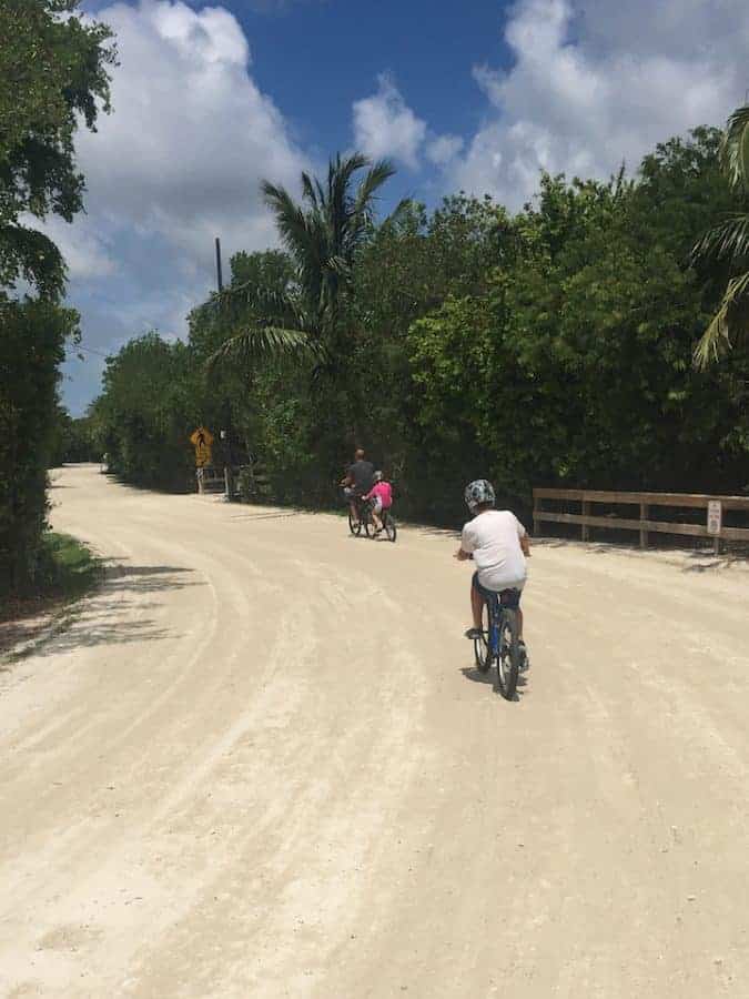 Family riding bikes on sand path in Sanibel Island florida