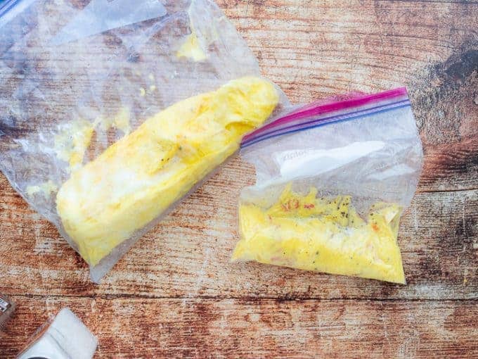 Boil in Bag Omelet, a camping recipe showing two freezer gallon ziploc bags on a wooden countertop with a salt shaker in front of the bags.