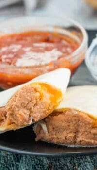 A tray of food on a plate, with Burrito and Refried beans