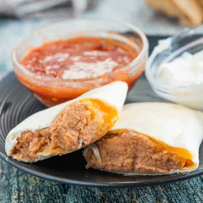 A tray of food on a plate, with Burrito and Refried beans