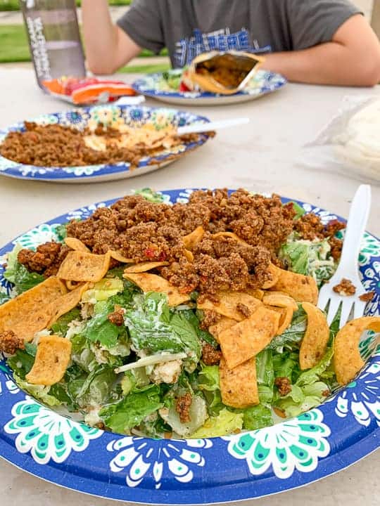 A group of people sitting at a table with a plate of taco salad