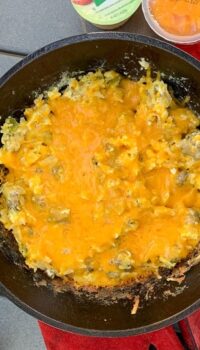 An egg Breakfast with cheese on top shown in a Cast Iron Skillet