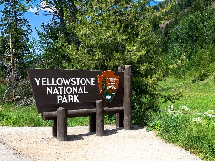 Yellowstone rv vacation showing the Yellowstone national park sign in front of woods.