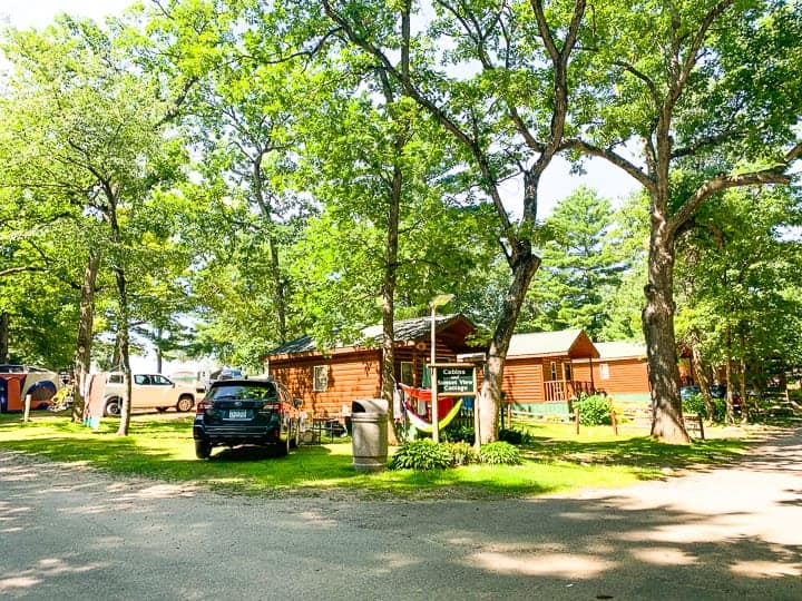 best camping in wisconsin showing some cabins and tree filled campsites at evergreen campground in wild rose, wi.