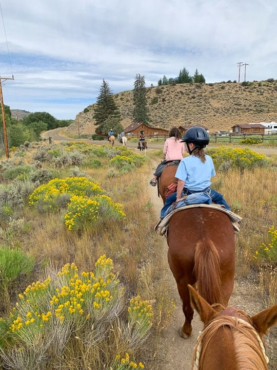 5 Kids riding horses enjoying a ride along a dirt path in Colorado headed to visit a local town next to a family dude ranch. 