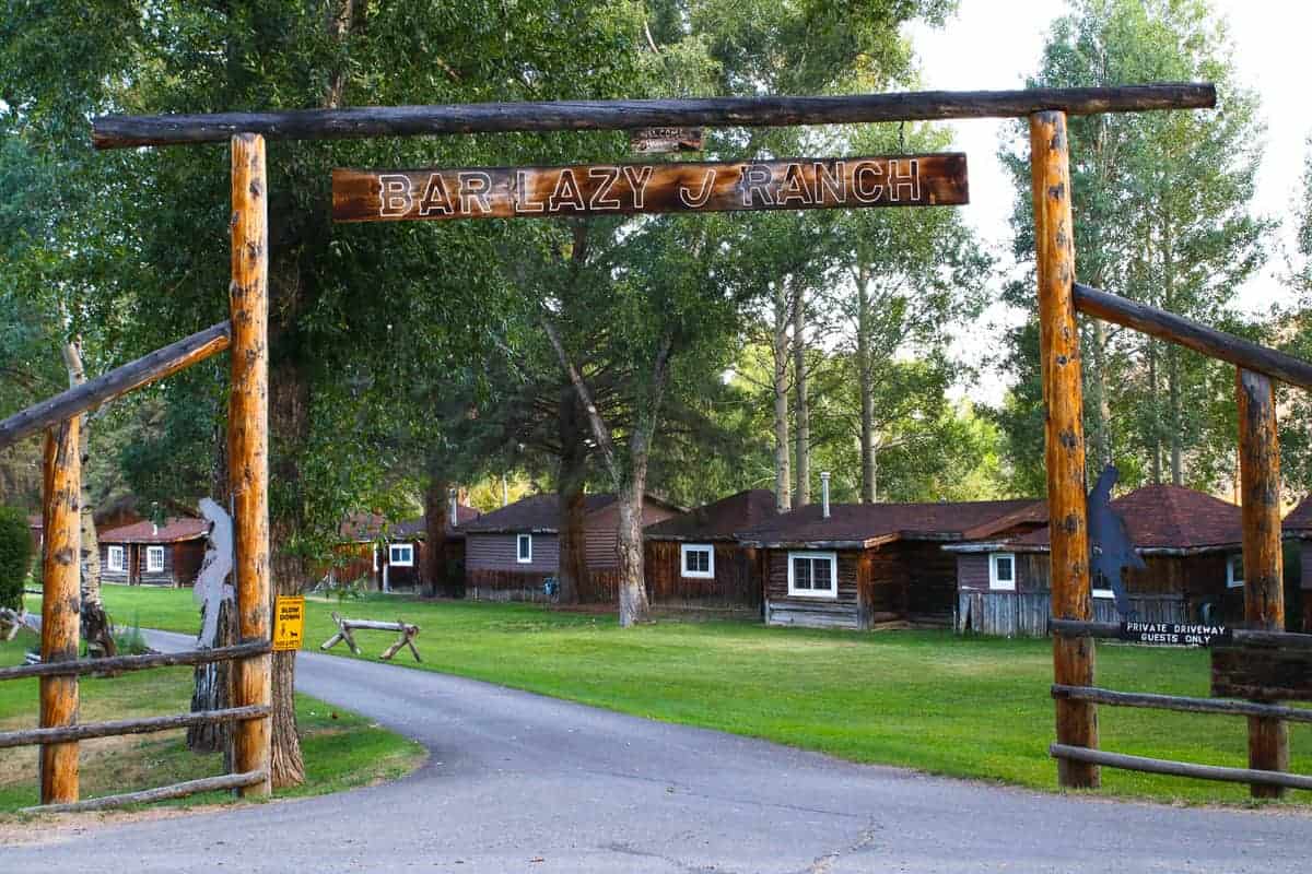 The entrance for Bar Lazy J Ranch, a Colorado ranch, with cabins in the background. 