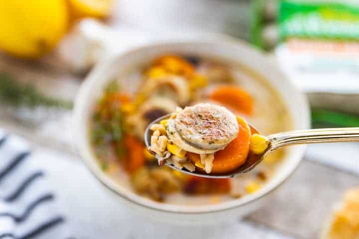 Chicken Sausage Soup, a recipe using pre-cooked chicken sausage, being shown in a small white bowl with a spoon showing the soup up close.