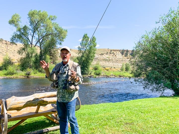 A man holding a fishing pole for a day of fly fishing next to a family dude ranch in Colorado.