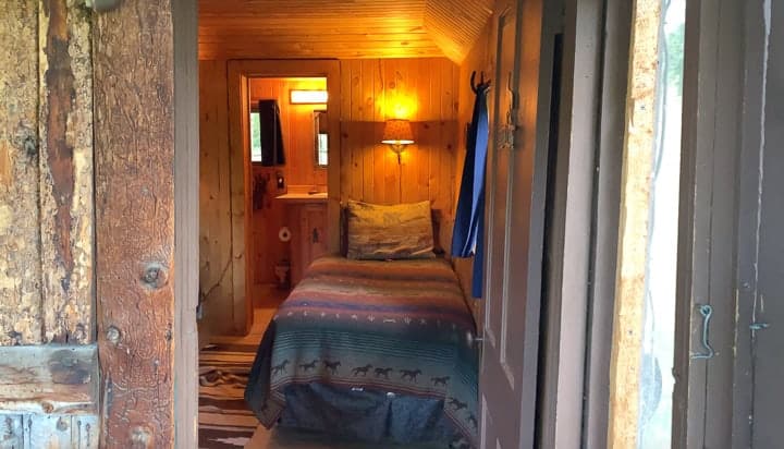 One side of a 2 bedroom log cabin showing a single bed and the bathroom.
