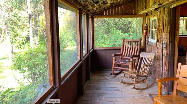 Rocking chairs on a porch of a log cabin at a family dude ranch in Colorado.