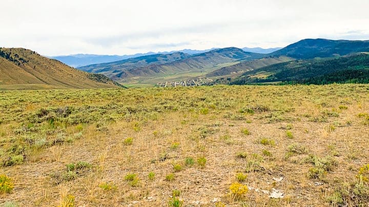 A view from up high of a small town in the distance surrounded by mountains.