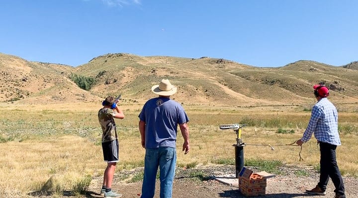 2 men and a teenager at a shooting range shooting clays