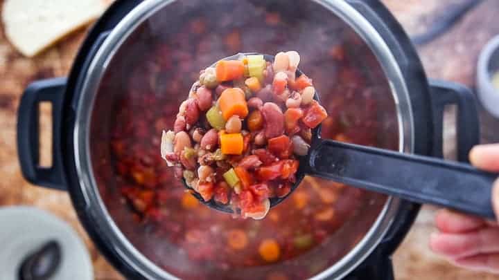 a top down view showing an instant pot filled with soup with a ladle scooping a serving of soup from the pot.